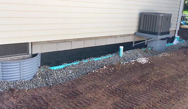 Exterior waterproofing and drainage work beside a home